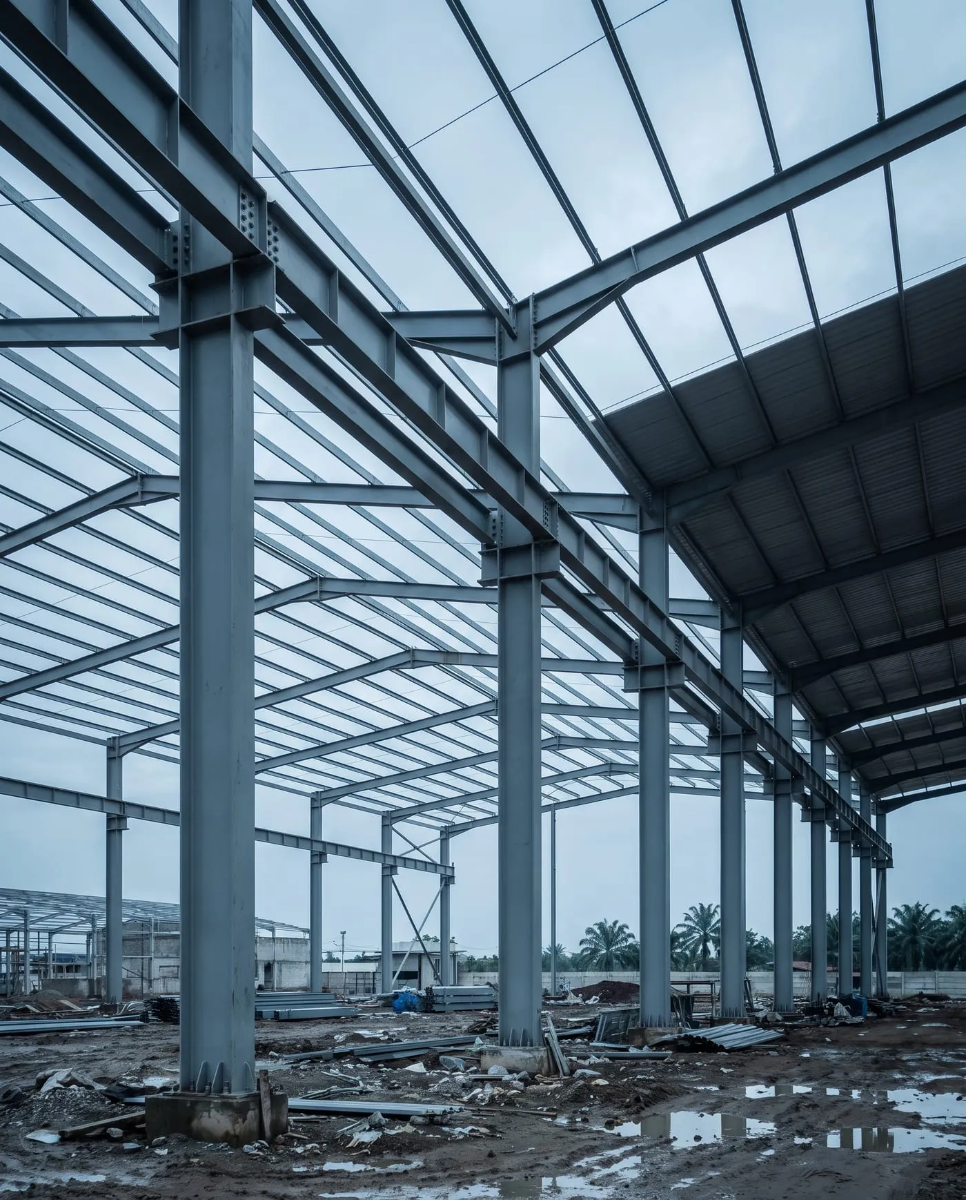 Rangka baja portal frame gudang bentang lebar dalam tahap ereksi, dilihat dari dalam bangunan.