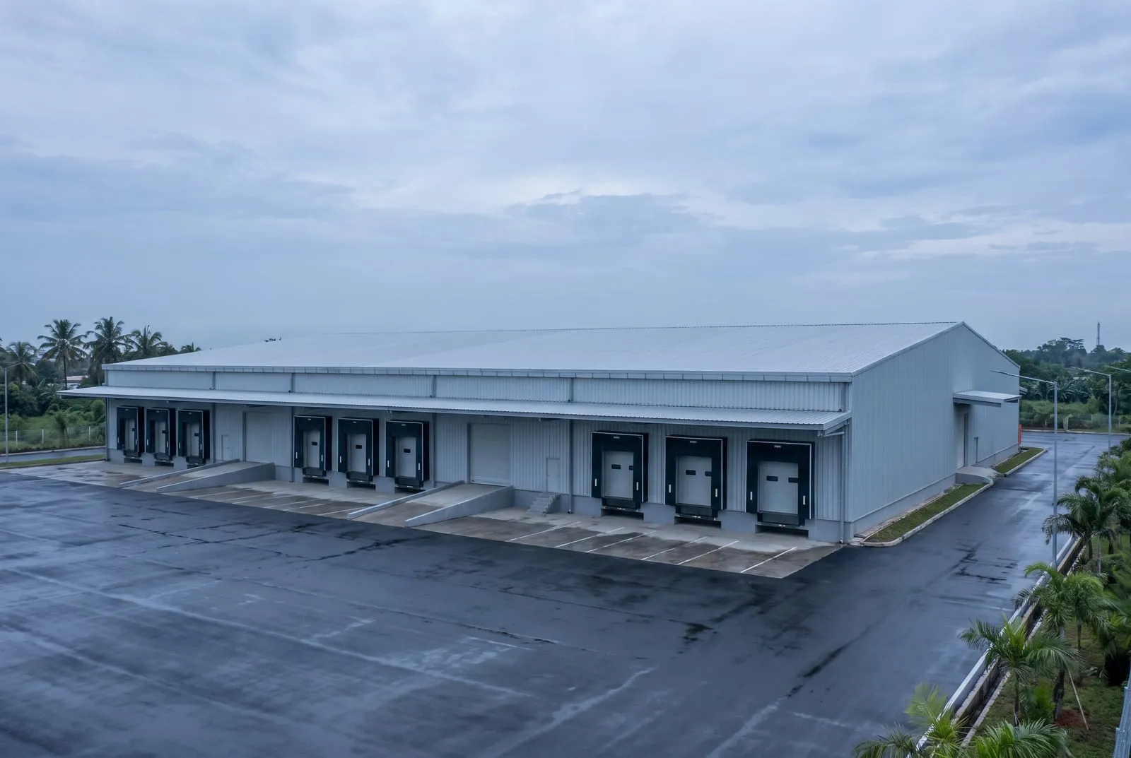 Tampak luar gudang logistik dengan dinding metal dan deretan pintu dok bongkar muat.