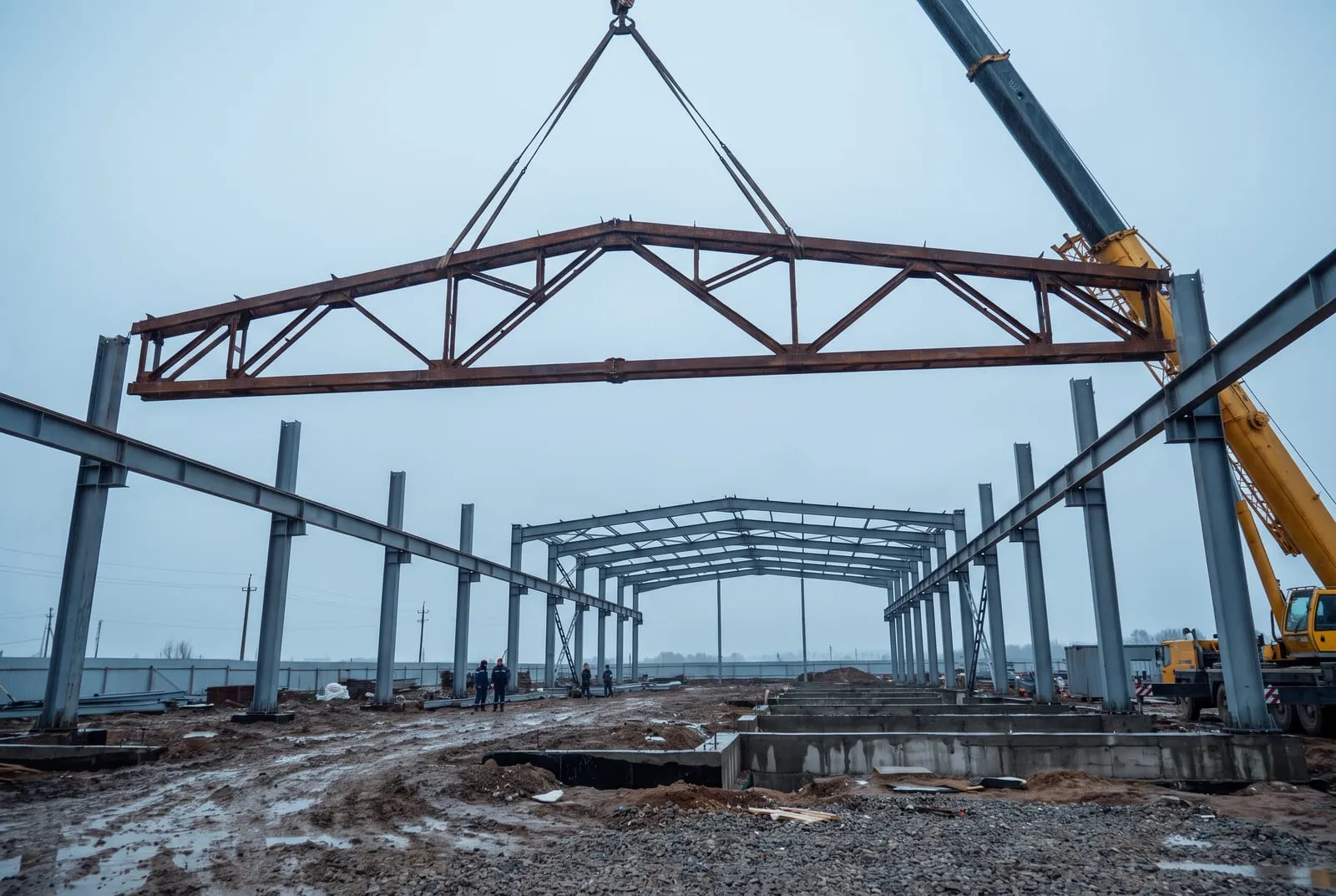 Pengangkatan satu unit rangka batang atap oleh crane roda pada tahap ereksi.