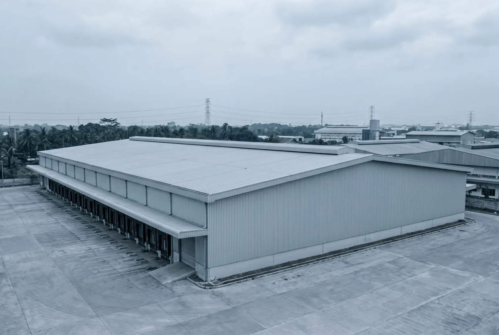 Tampak luar gudang bentang lebar dengan dinding metal panjang dan atap landai.
